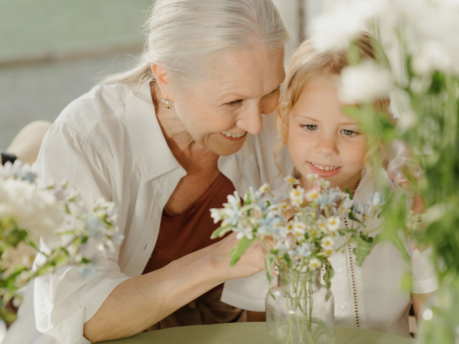 An older woman and a girl smiling together over a jar of wildflowers — where your medical records travel under an insurance application